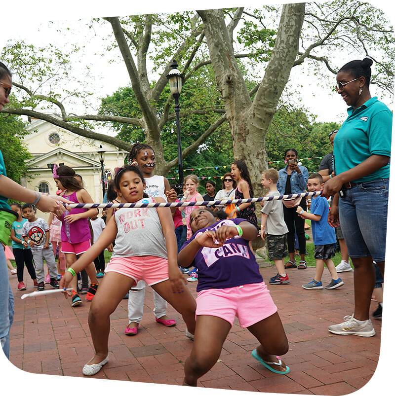 Children going under limbo stick during museum carnival
