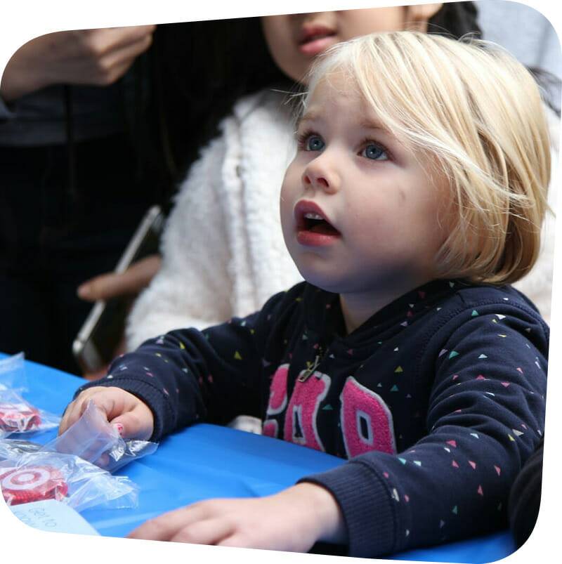 child looking up while leaning on a table