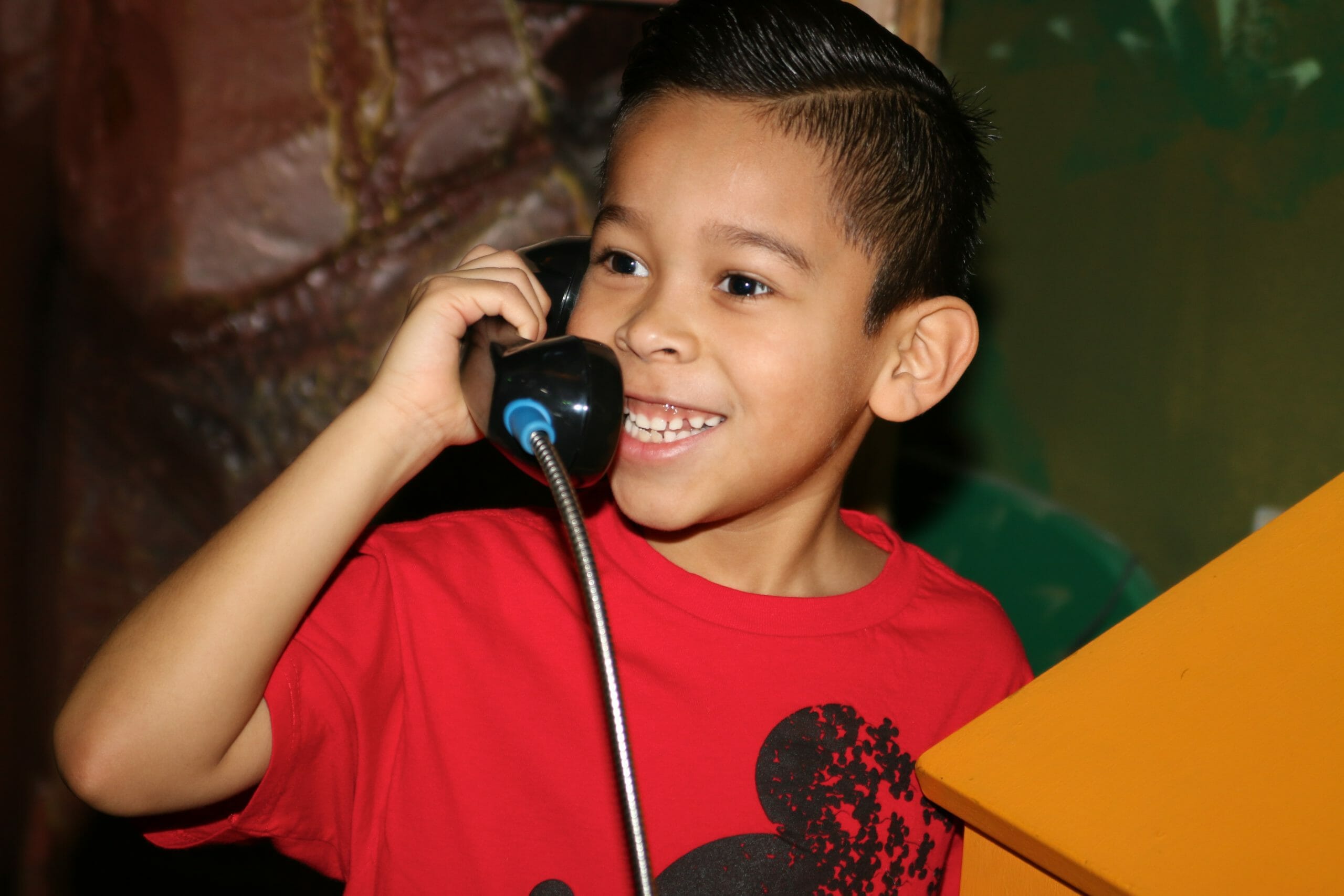 Child smiling while talking on the phone in Great Explorations exhibit.