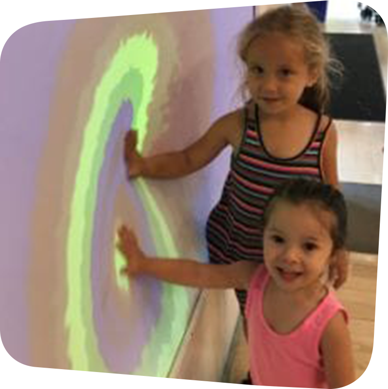 two children touching colorful wall
