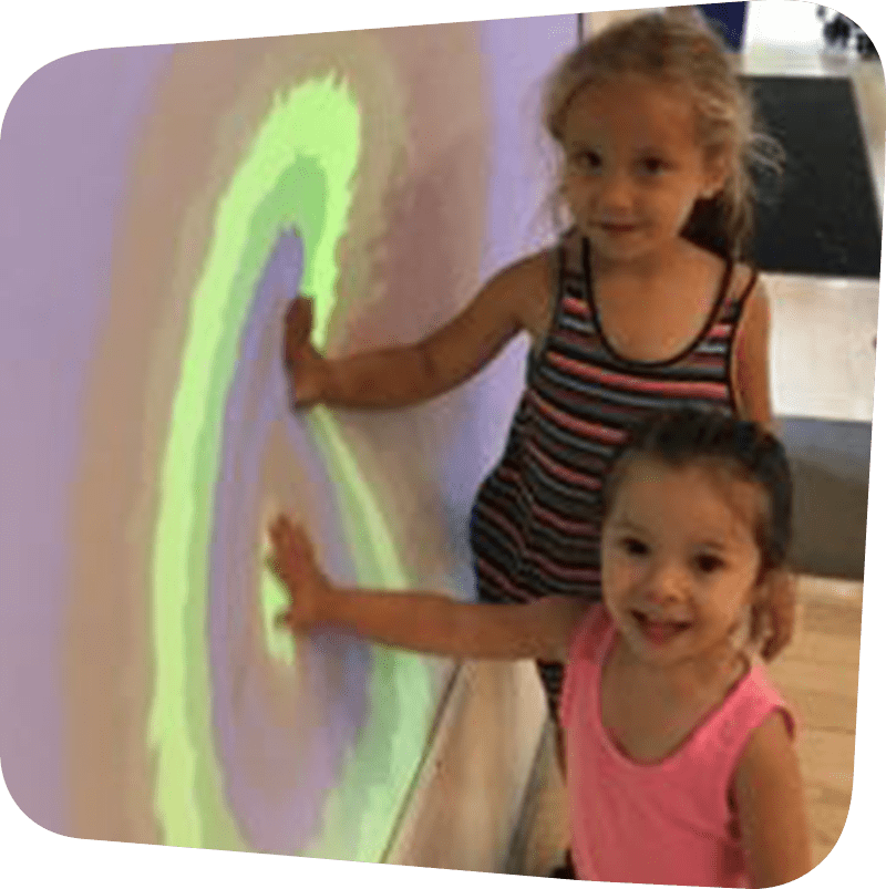 two children touching colorful wall