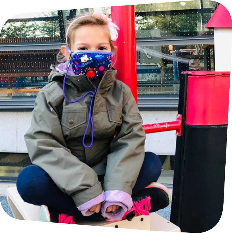 child smiling in sea of boats with facemask.