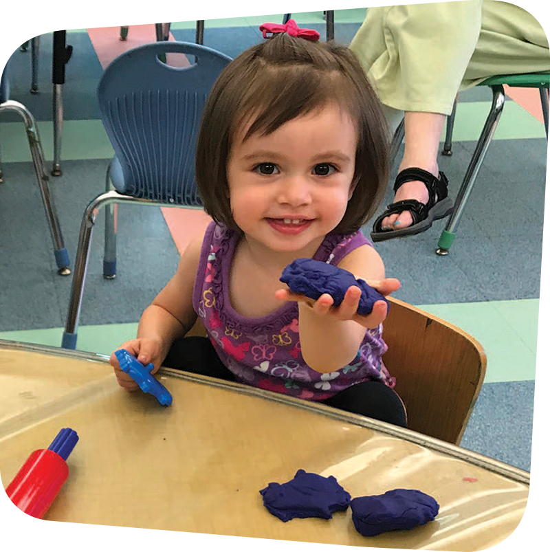 Child holding purple play dough.