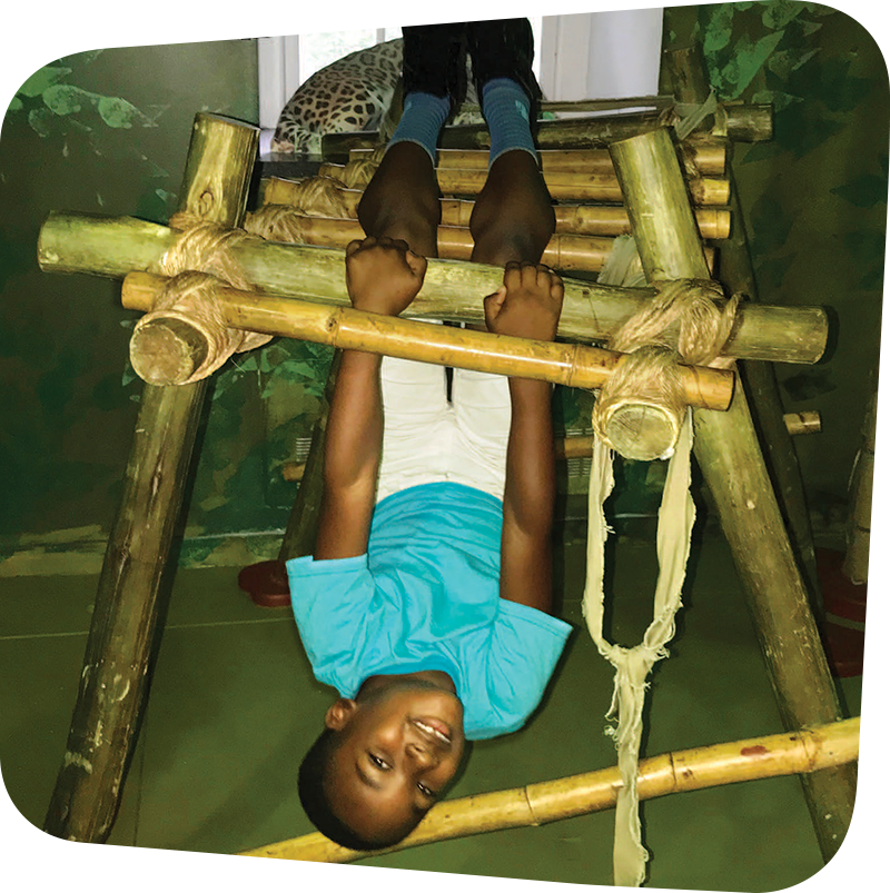 Child hanging from bamboo bars in Great Exploration exhibits.