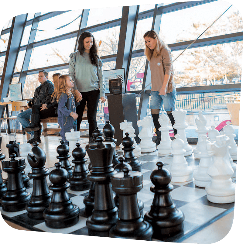 Child and adults playing chess in our big games exhibit.