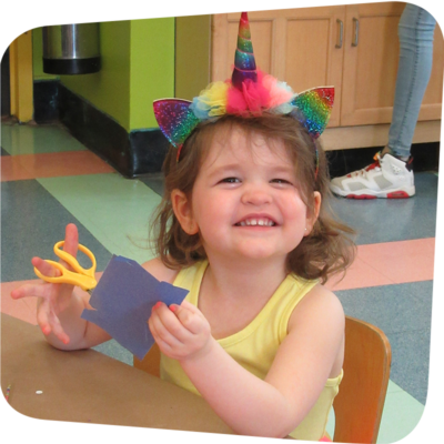 child with art supplies smiling at the camer