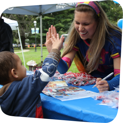 Ready Girl high fiving visitor at a booth on the meadow in front of the Children's Museum