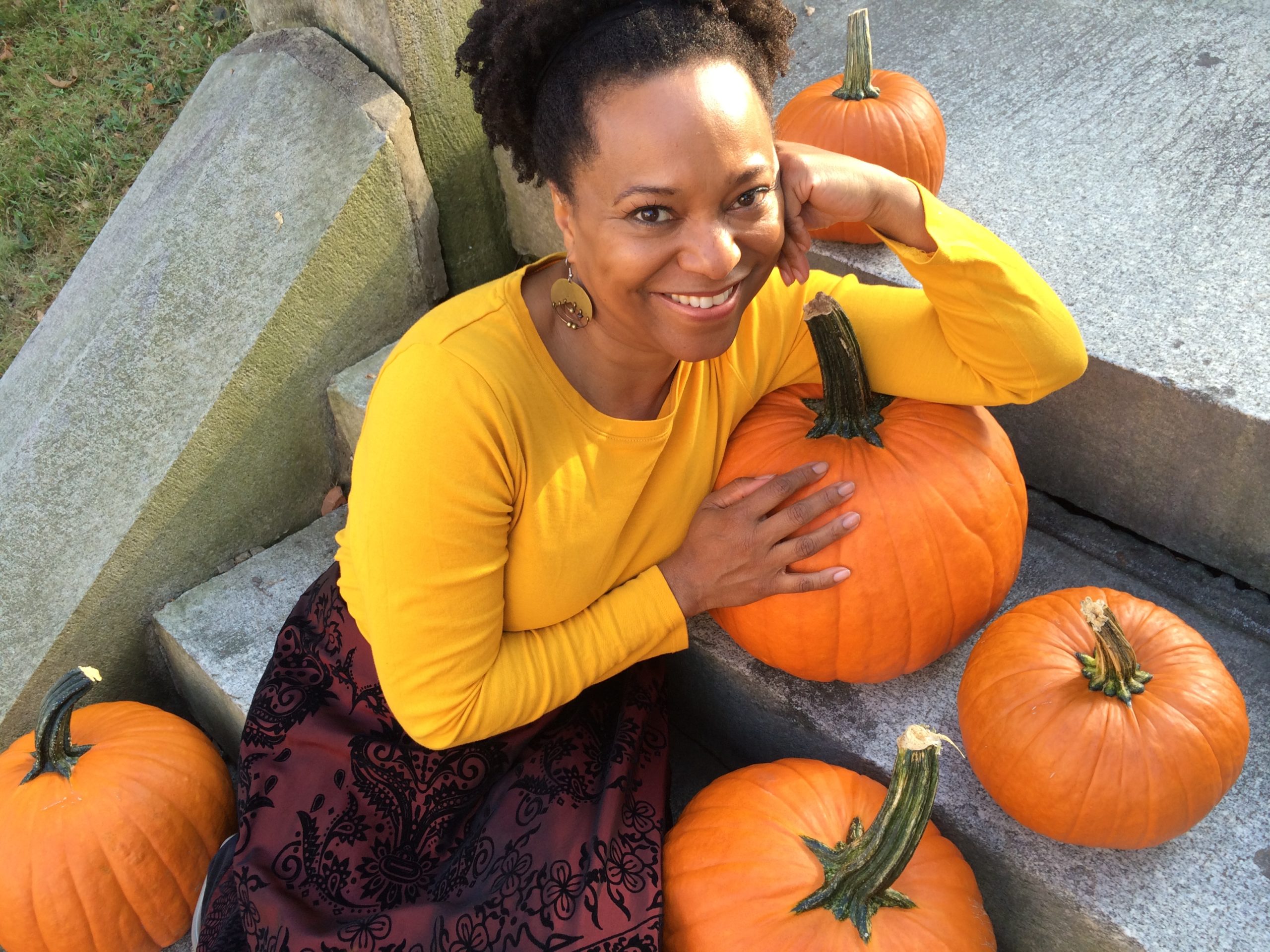 April Armstrong smiling and resting on pumpkins