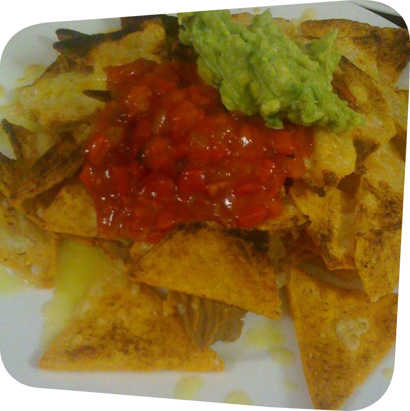 white plate with tortilla chips topped with cheese, salsa and guacamole