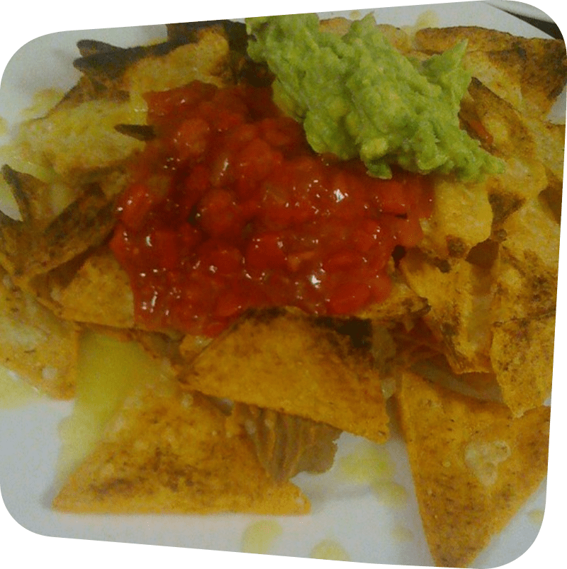 white plate with tortilla chips topped with cheese, salsa and guacamole