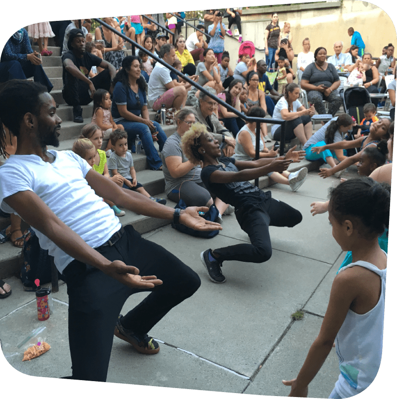 crowd watching dancers lean nearly 90 degrees backwards with arms outstretched