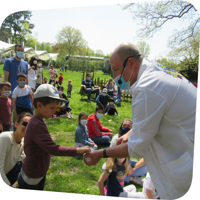 Science presenter showing example to child in the crowd on the meadow outside the Museum