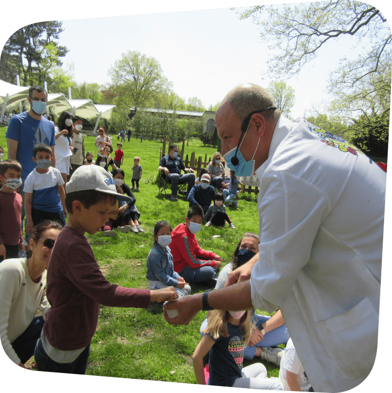 Science presenter showing example to child in the crowd on the meadow outside the Museum