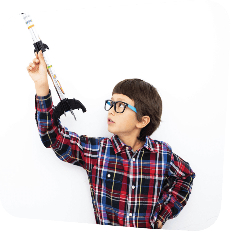 boy holding a model rocket in one hand and aiming it at the sky
