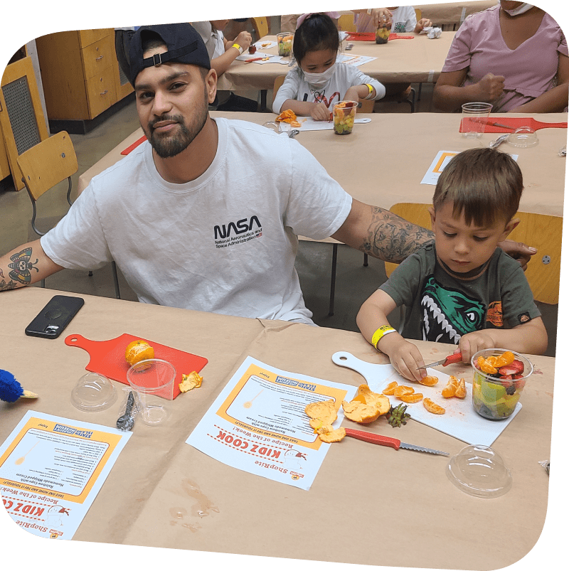 Dad with child who is very focused on chopping oranges for Kidz Cook Recipe