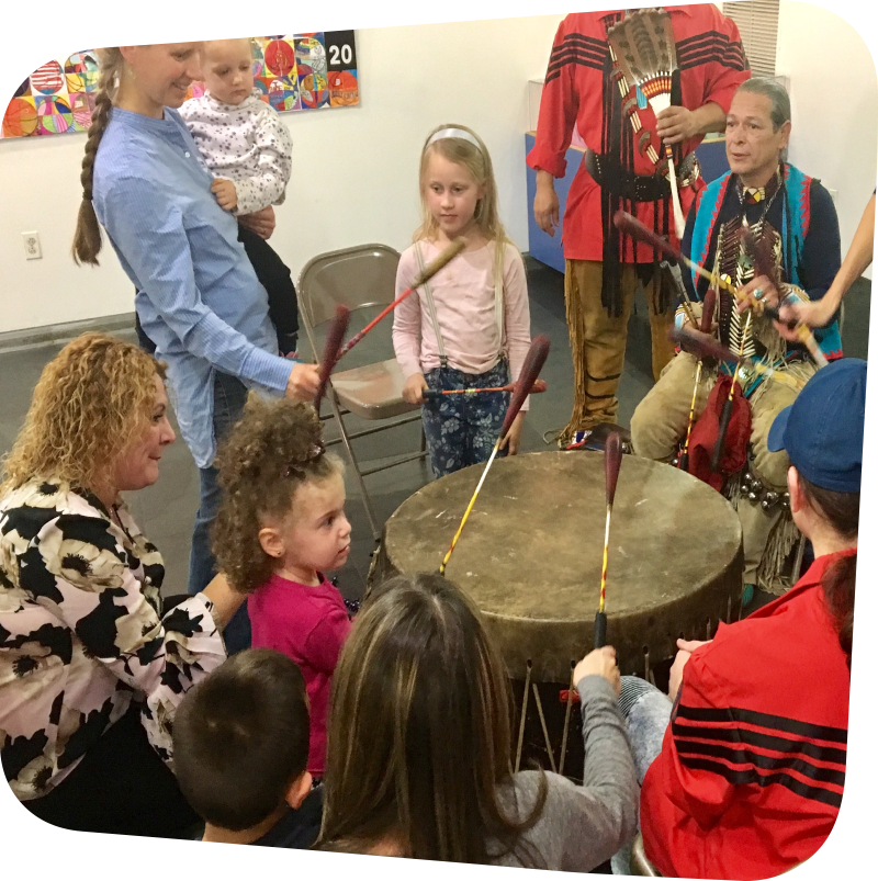 children and parents surrounding representatives from the Red Storm Drum and Dance Troupe with large drum in the middle