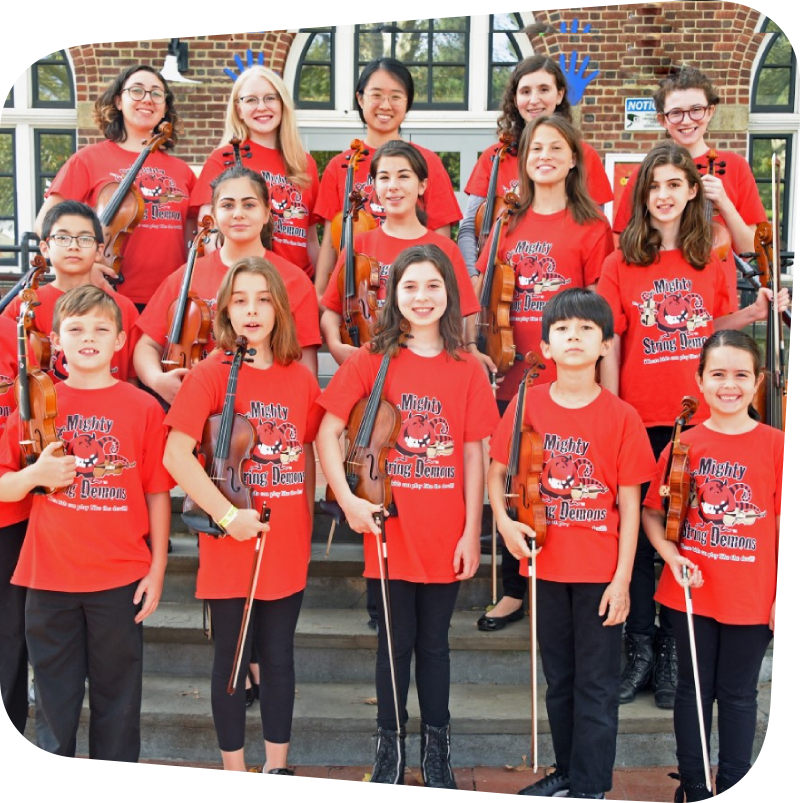 15 children standing in 3 rows of 5 holing violins wearing matching red t-shirts with the Mighty String Demons logo on it