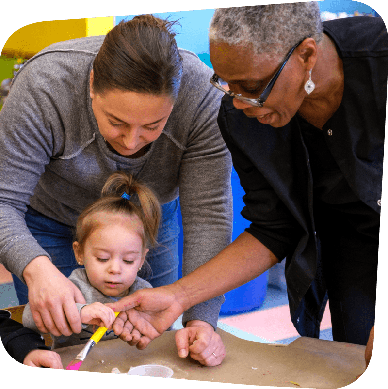 Dr. Greene and a parent helping young child with her art creation