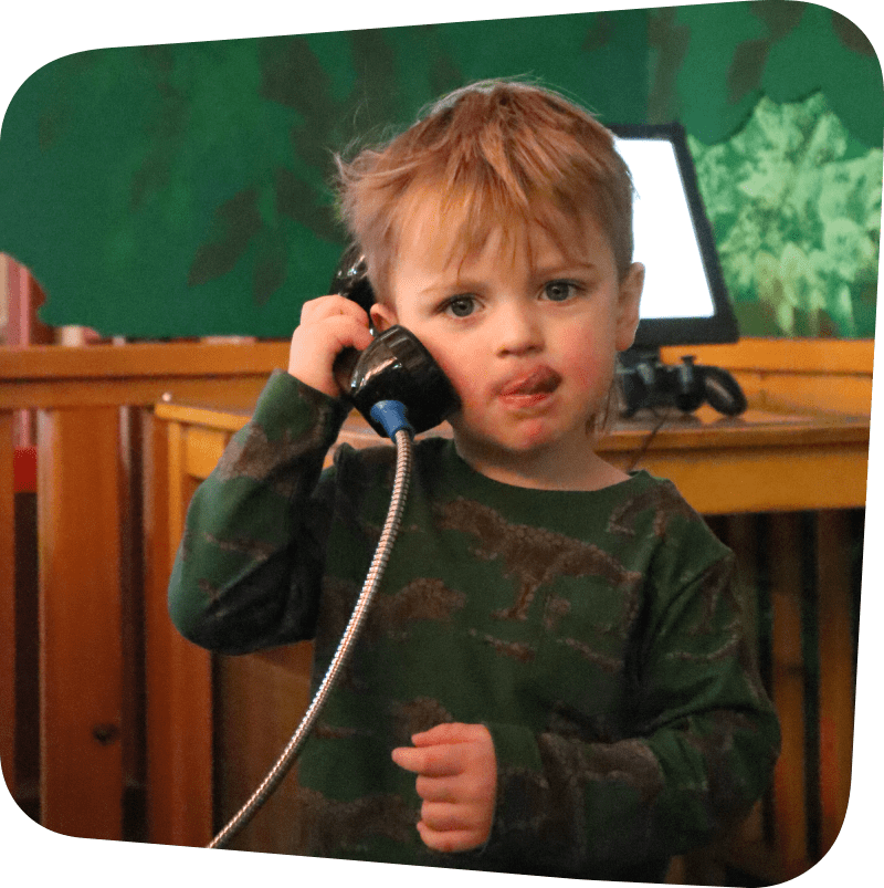 Child featured on a phonebooth style phone while sticking their tongue out to the side