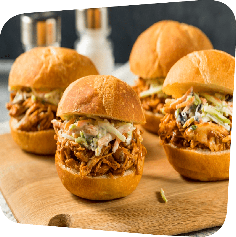 Four BBQ sliders with slaw on a butcher block slab