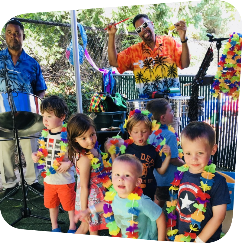 children wearing flower necklaces on stage with music performers