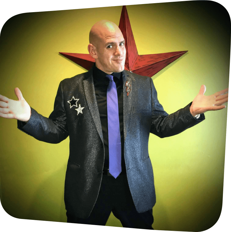 The magician Magical Matt in a suit looking sideways at the viewer