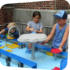 Three children playing at different stations of the water table in Sea of Boats an outdoor exhibit