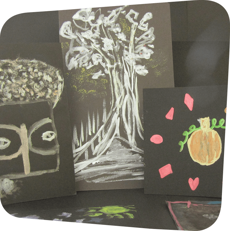 Paintings of an African mask, a tree and a pumpkin made from metallic paints on black paper