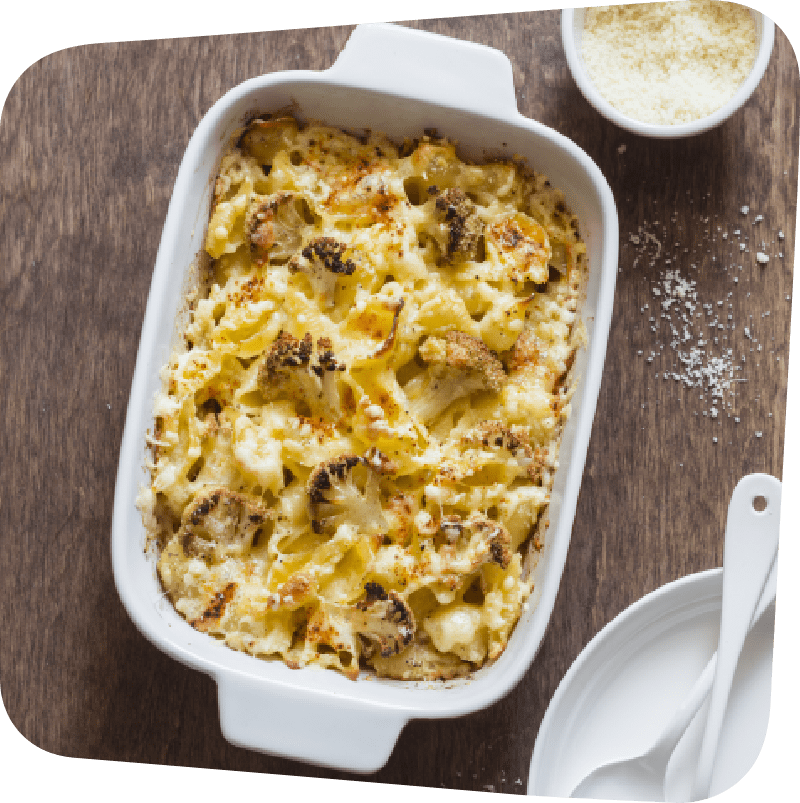 Cooked pan of cauliflower mac n cheese on a brown wooden table.