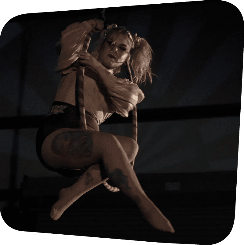 An acrobat sitting aloft in a hoop